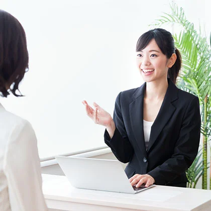 テーブル越しに相談者へ資料を示して説明する女性スタッフ